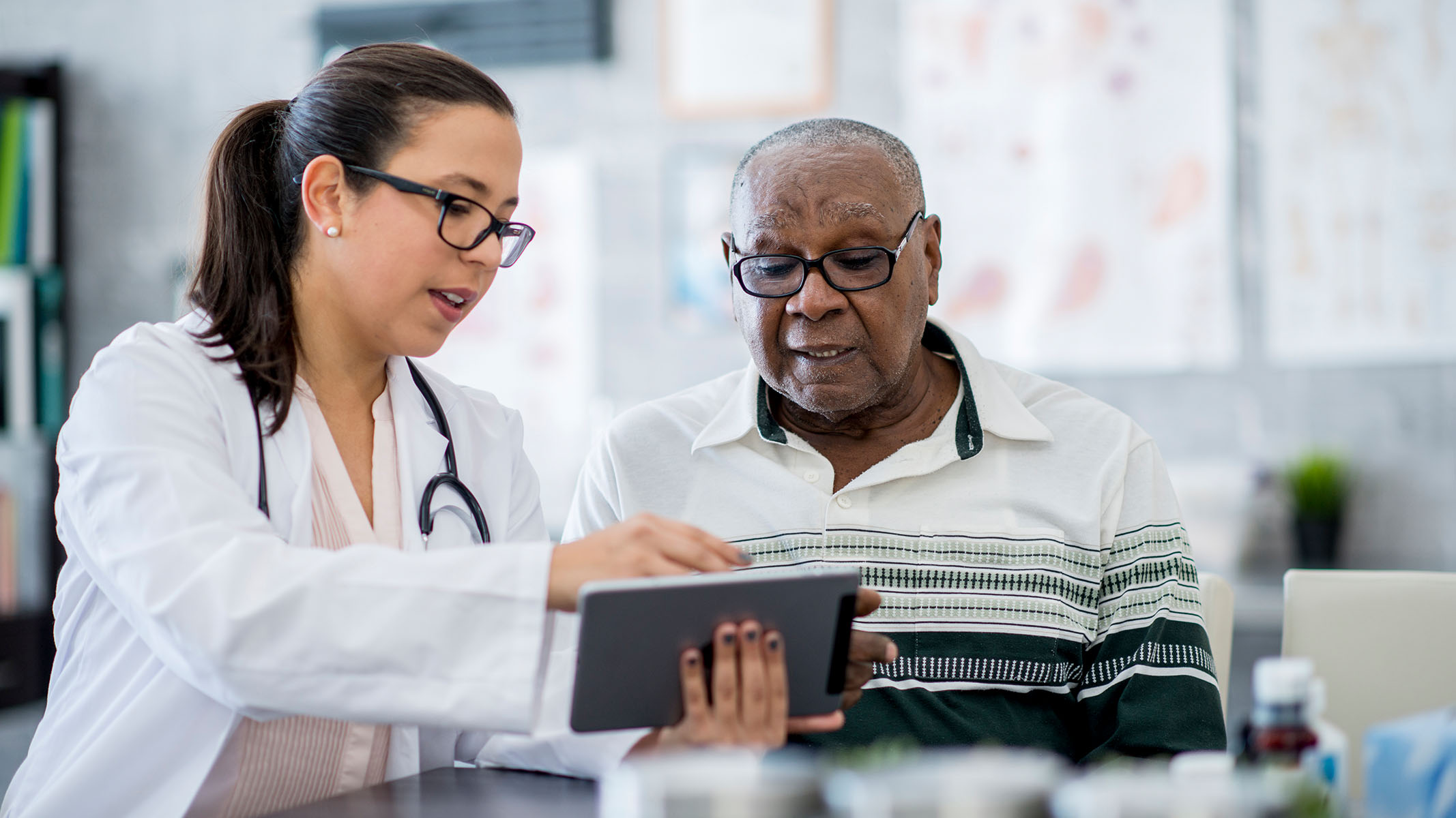 Doctor pointing at tablet talking to senior patient