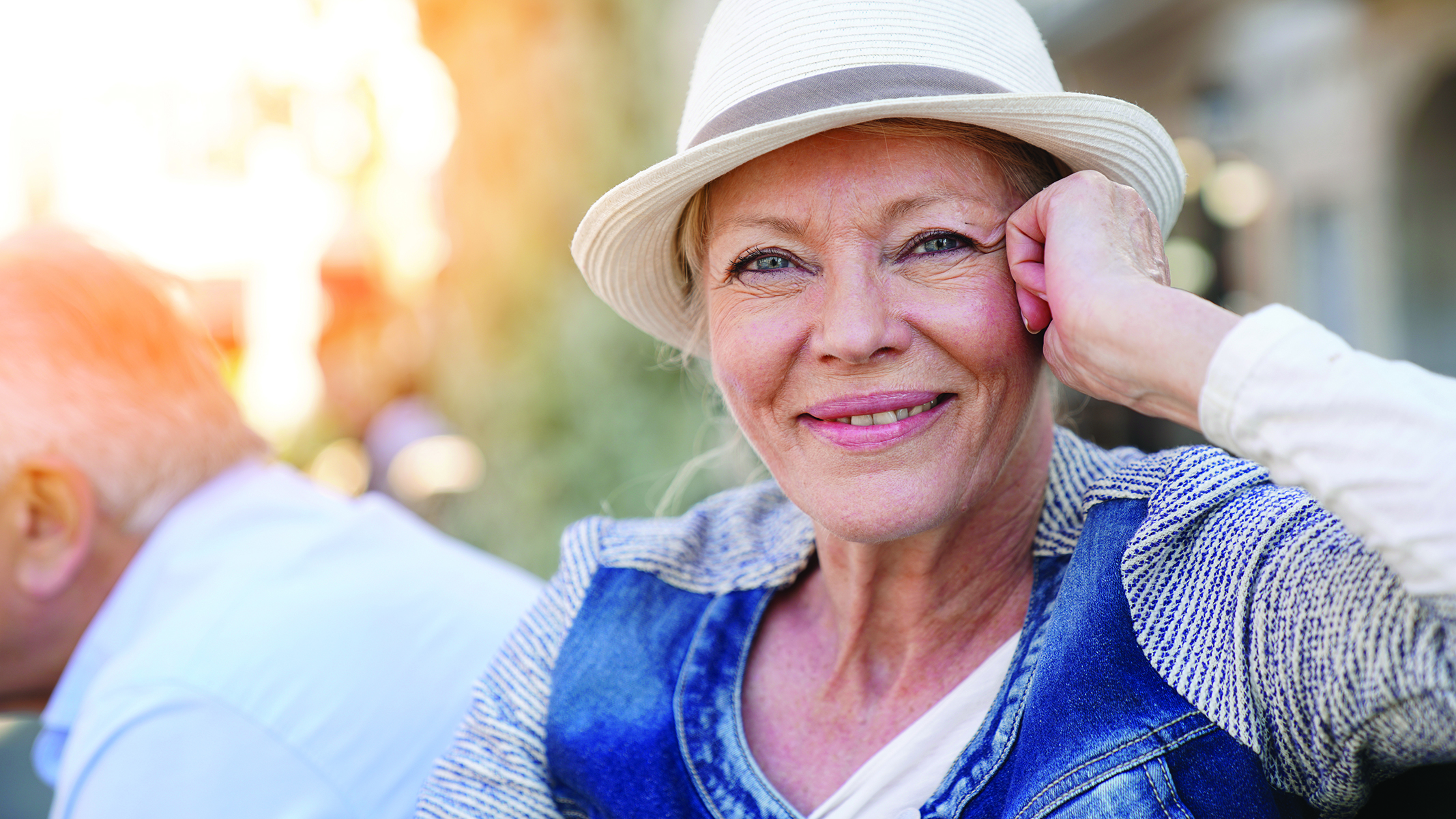 Senior woman wearing a hat smiling while looking at the camera.