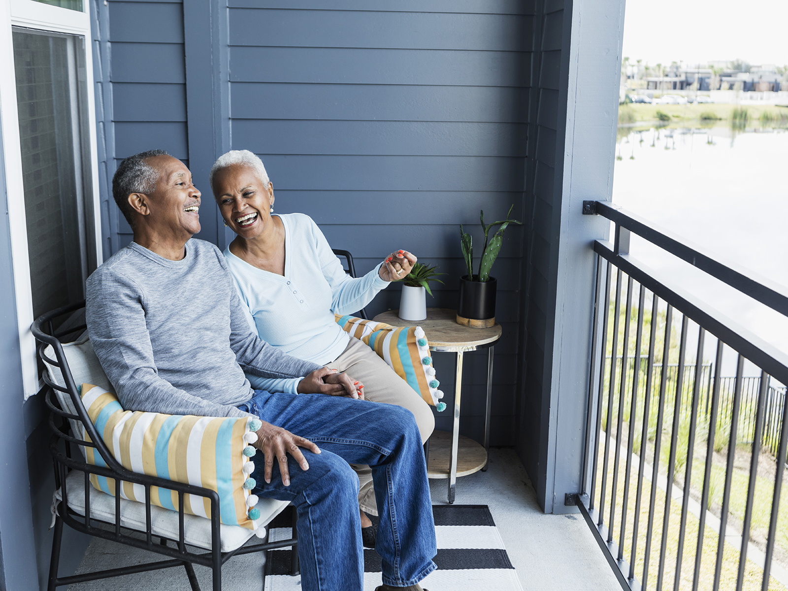 Senior couple laughing together while sitting on a balcony.