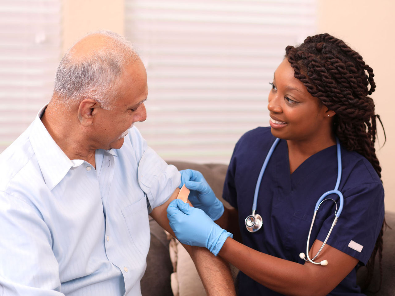 Senior man with health care professional applying a bandage.