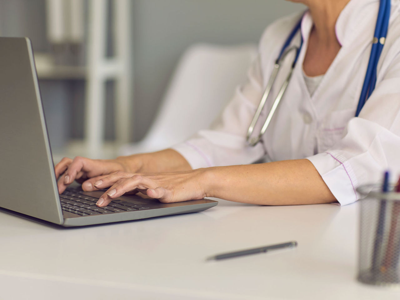 Healthcare professional typing on a laptop.
