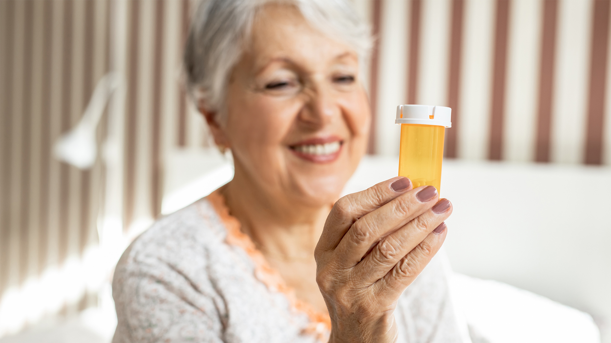 Mujer mayor sosteniendo un frasco de medicamento recetado.