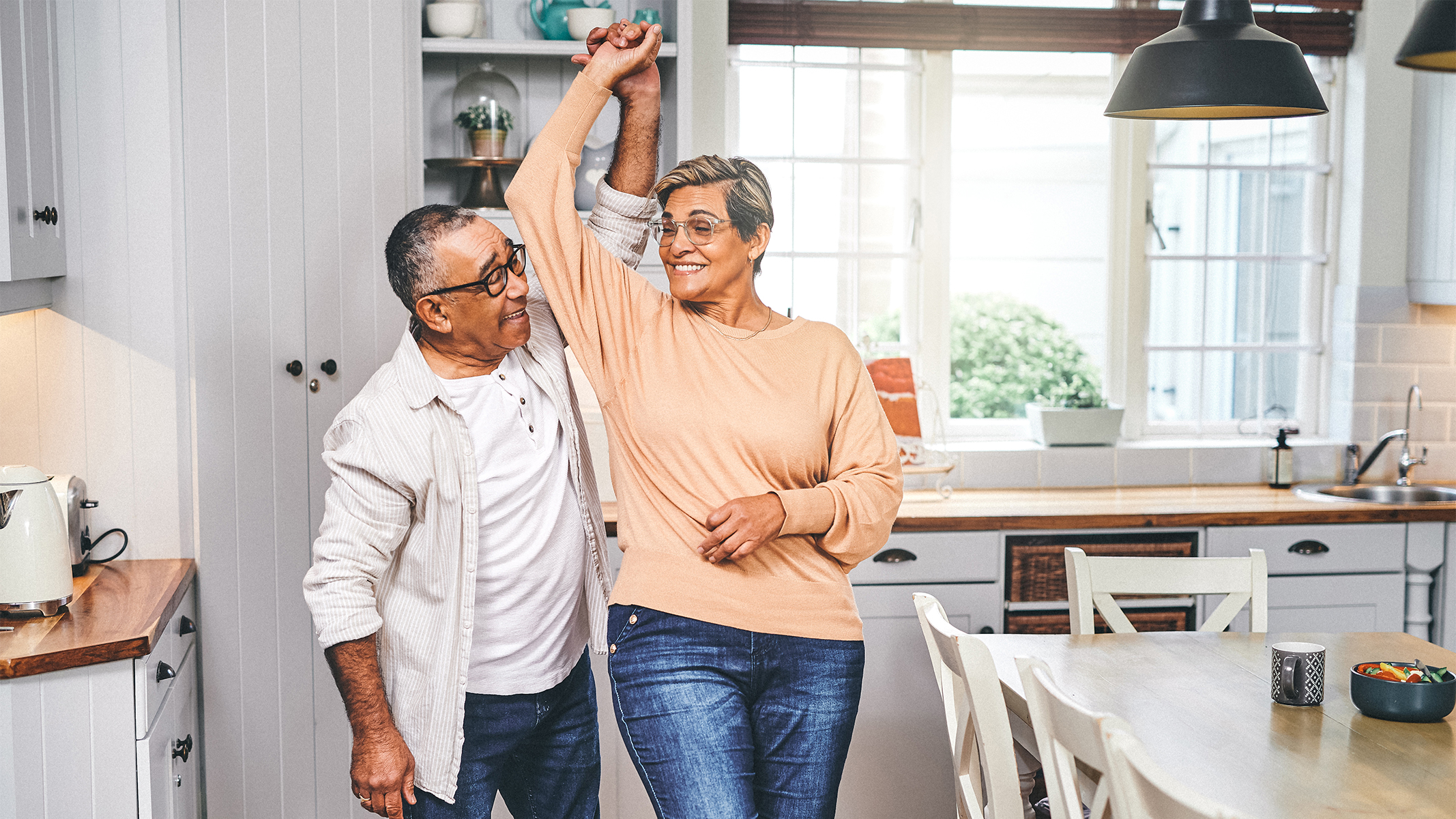  Senior couple dancing in kitchen.