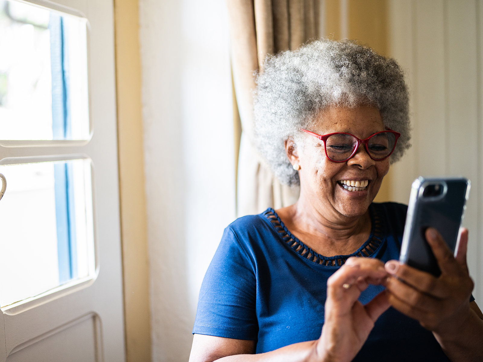 Senior woman using mobile phone indoors.