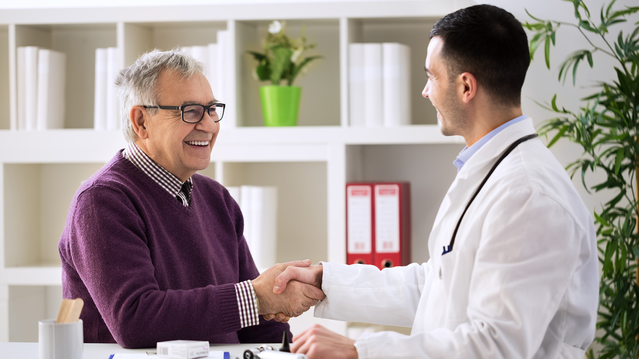  Senior man shaking hands with a doctor in an office.