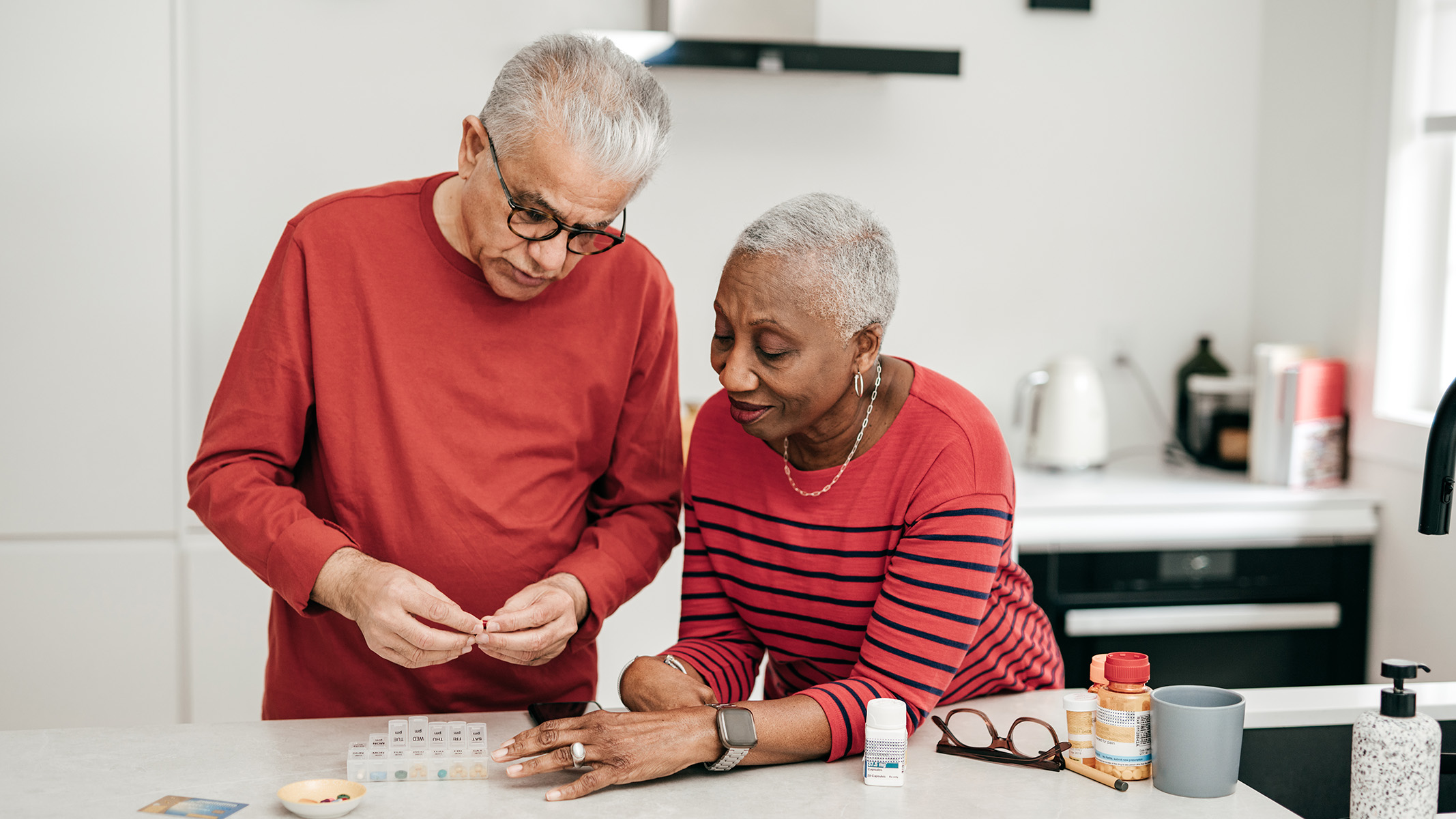  Senior couple filling a pill organizer in the kitchen.}