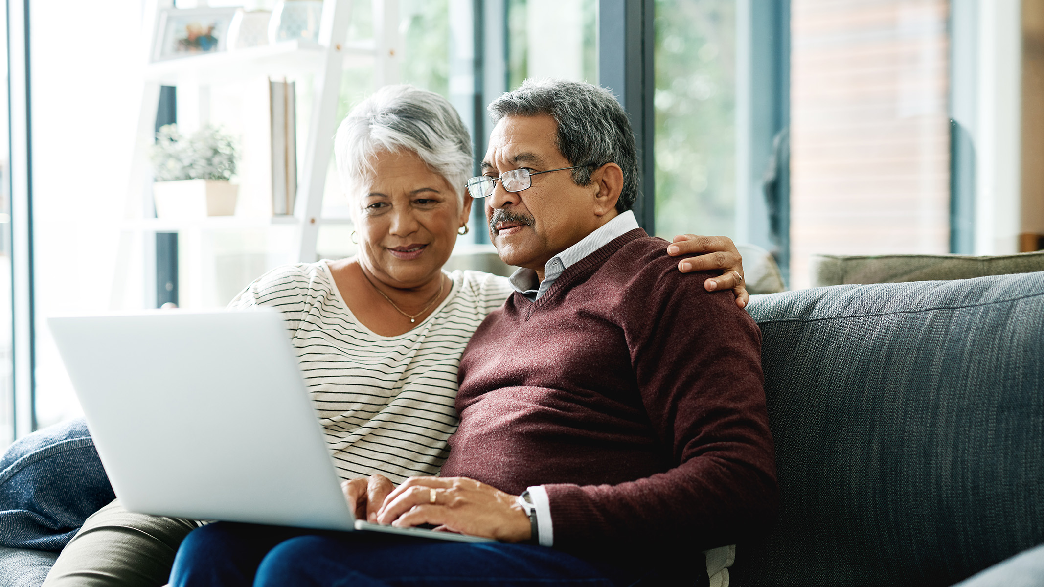  Senior couple looking at a laptop on the couch.
