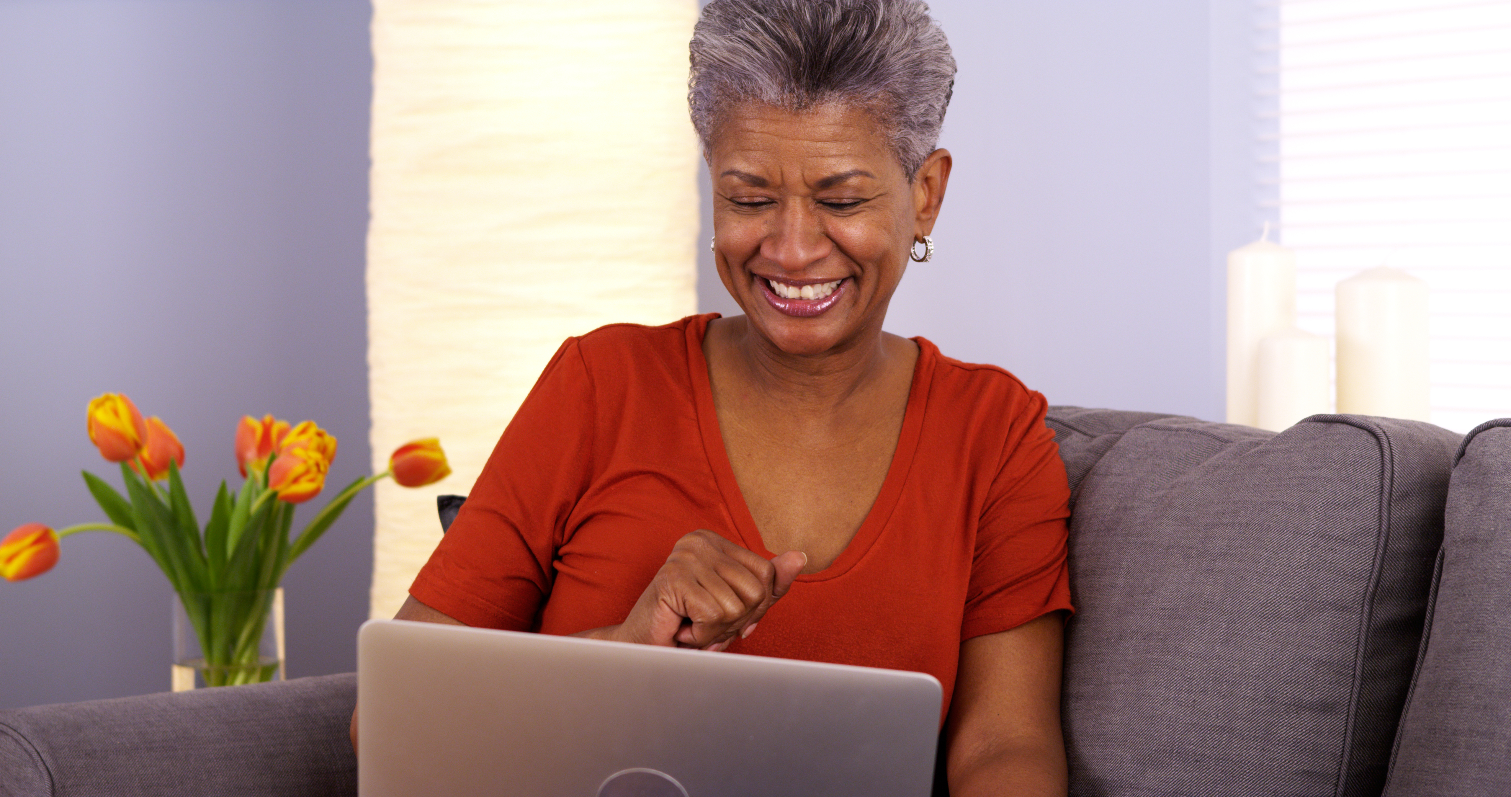 Mujer mayor sonriendo al computador portátil