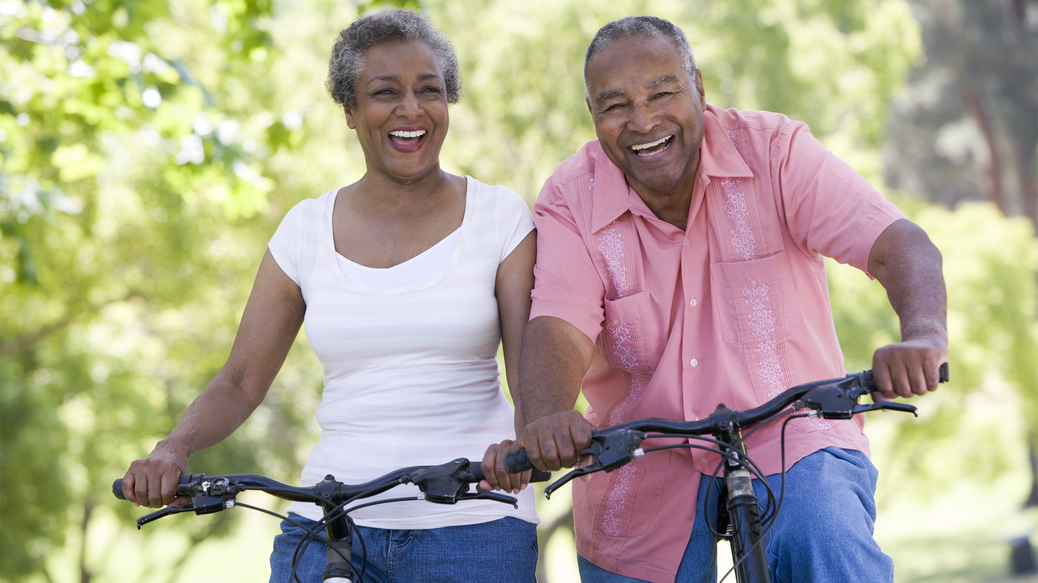 Senior couple smiling while riding bicycles.