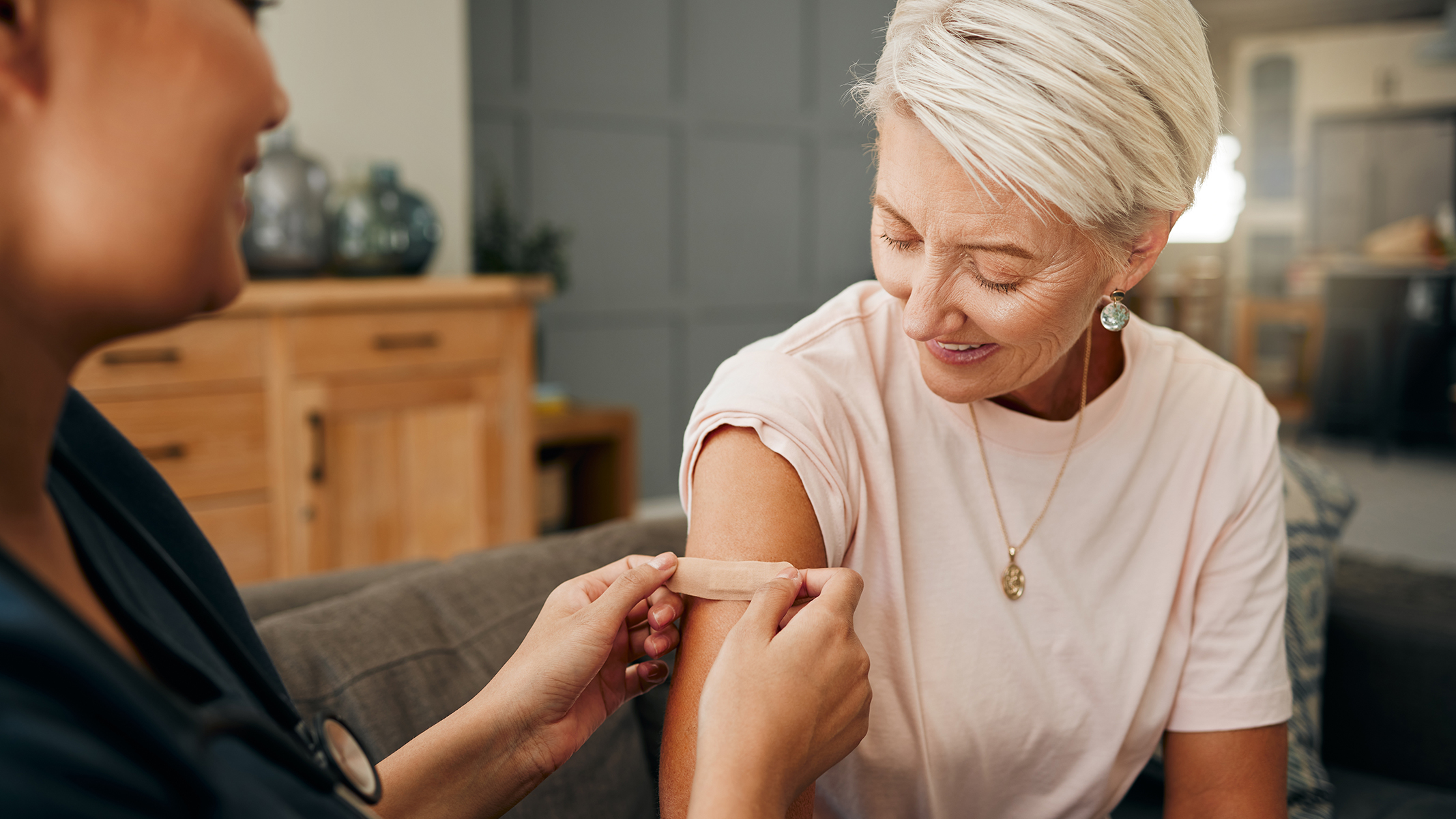 Doctor putting a bandage on senior woman.