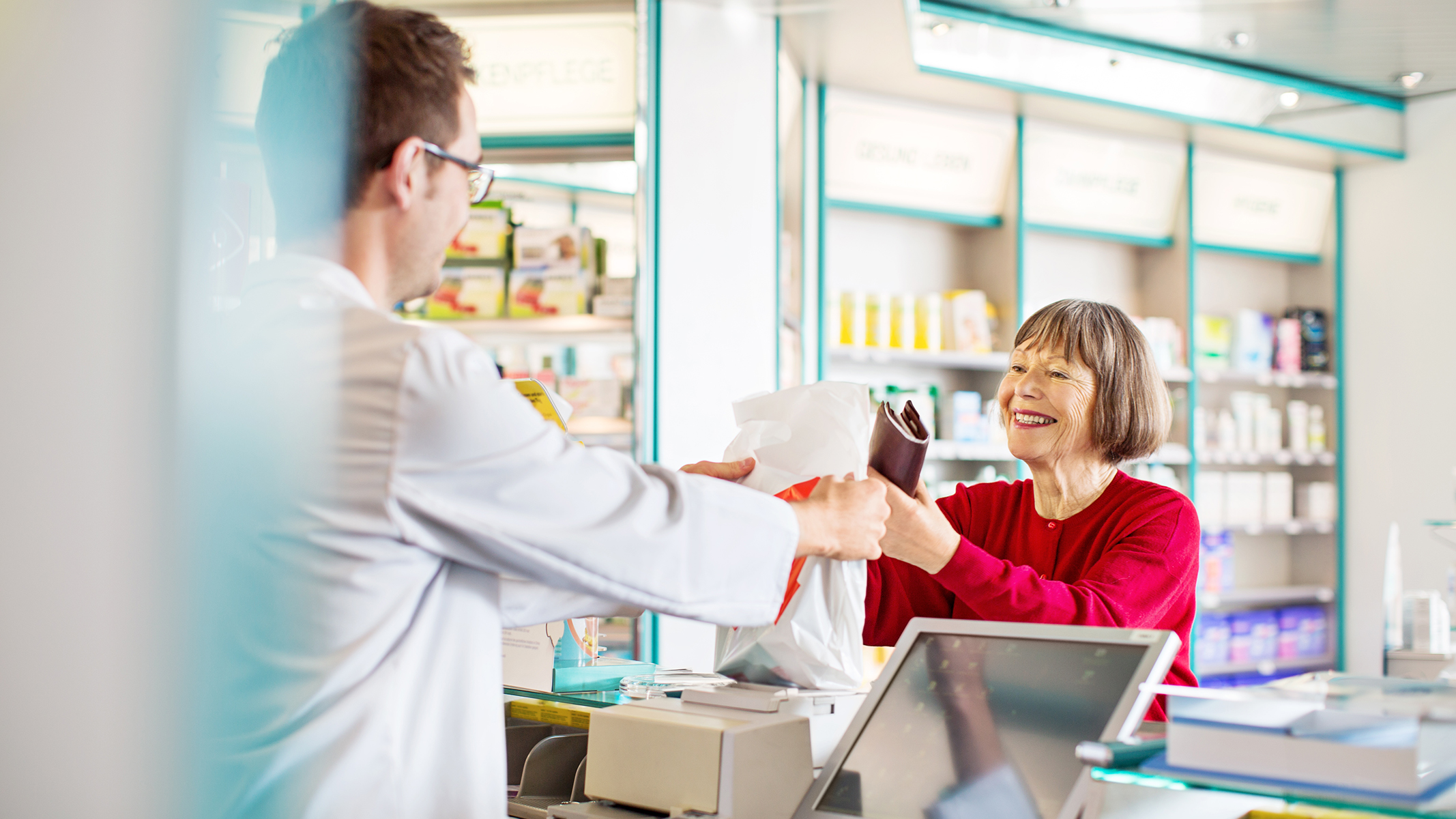 Pharmacist giving prescription medication to senior woman.