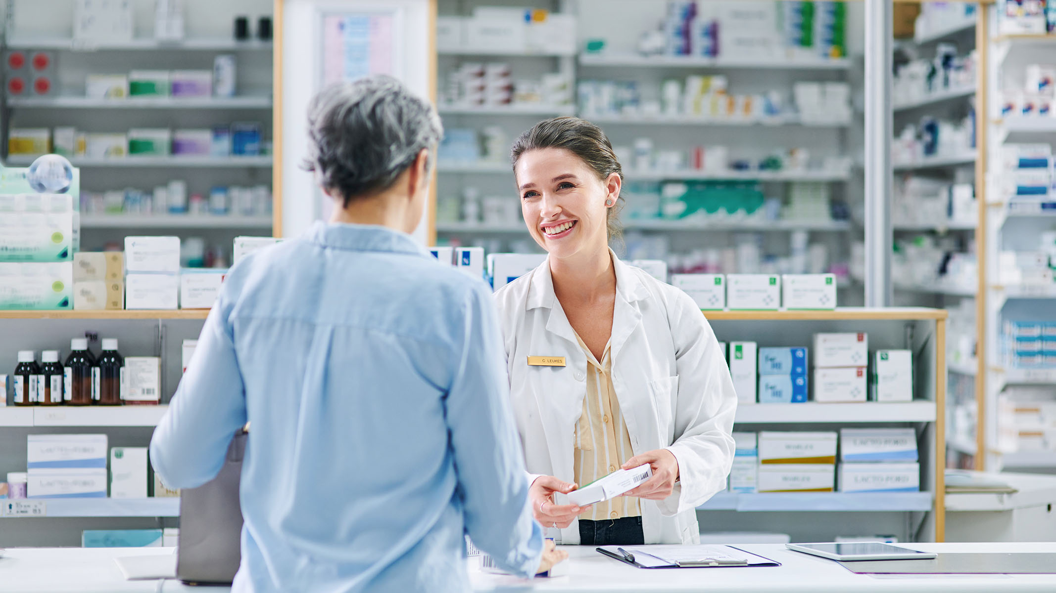 Farmacéutico ayudando a una mujer mayor en un mostrador de ventas