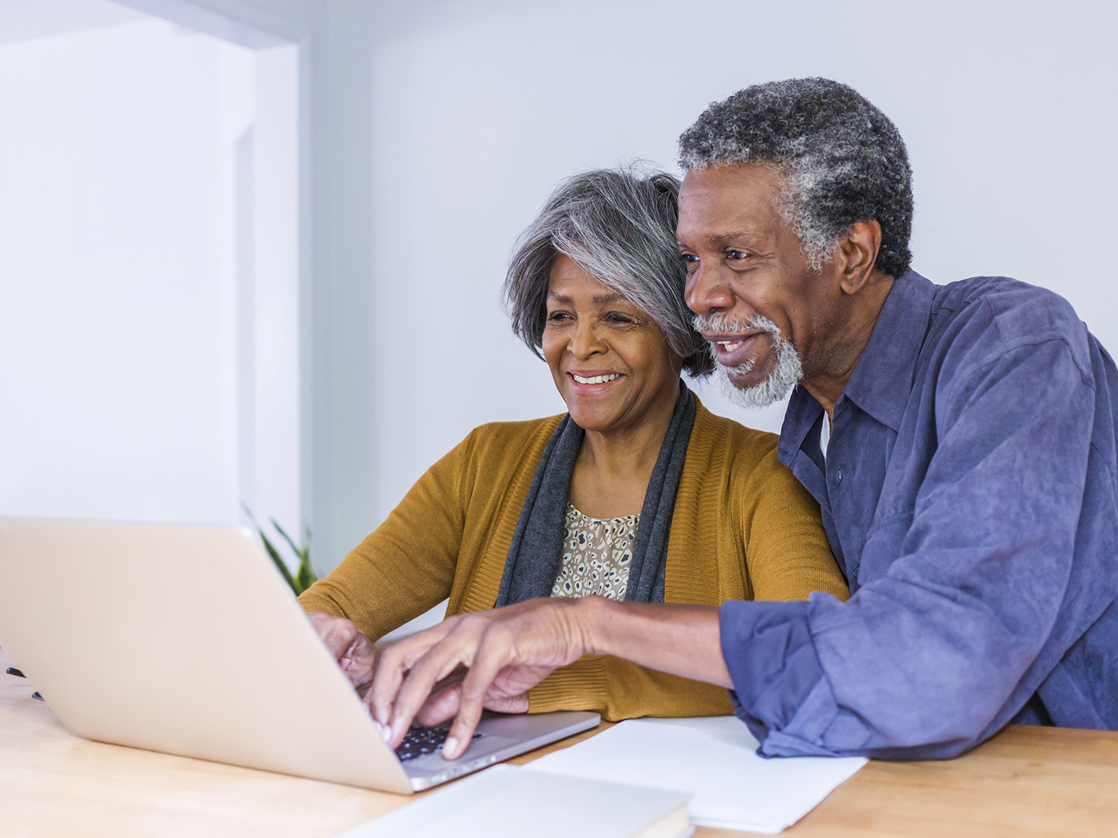 Senior couple smiling while using laptop.