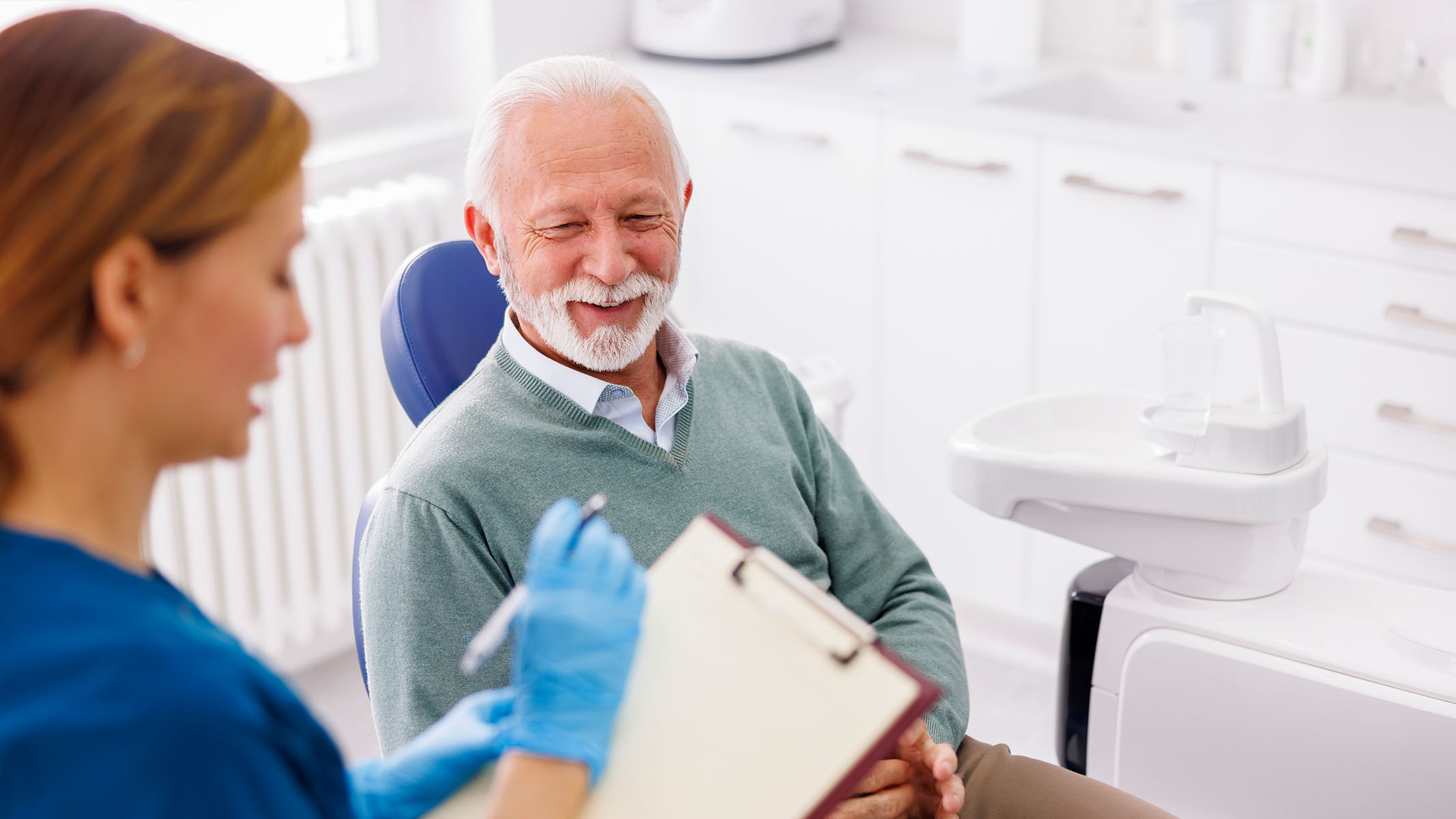 Hombre mayor hablando con un dentista.