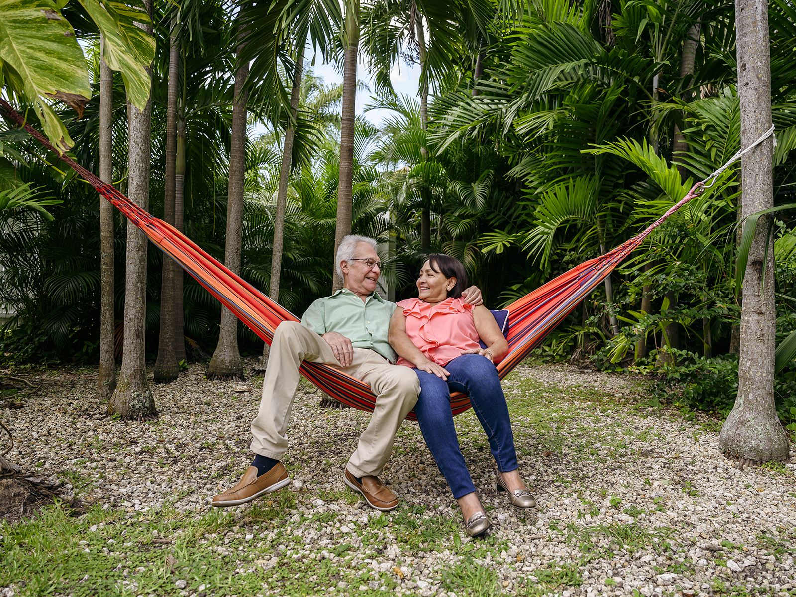 Pareja de personas mayores relajándose en una hamaca en el jardín