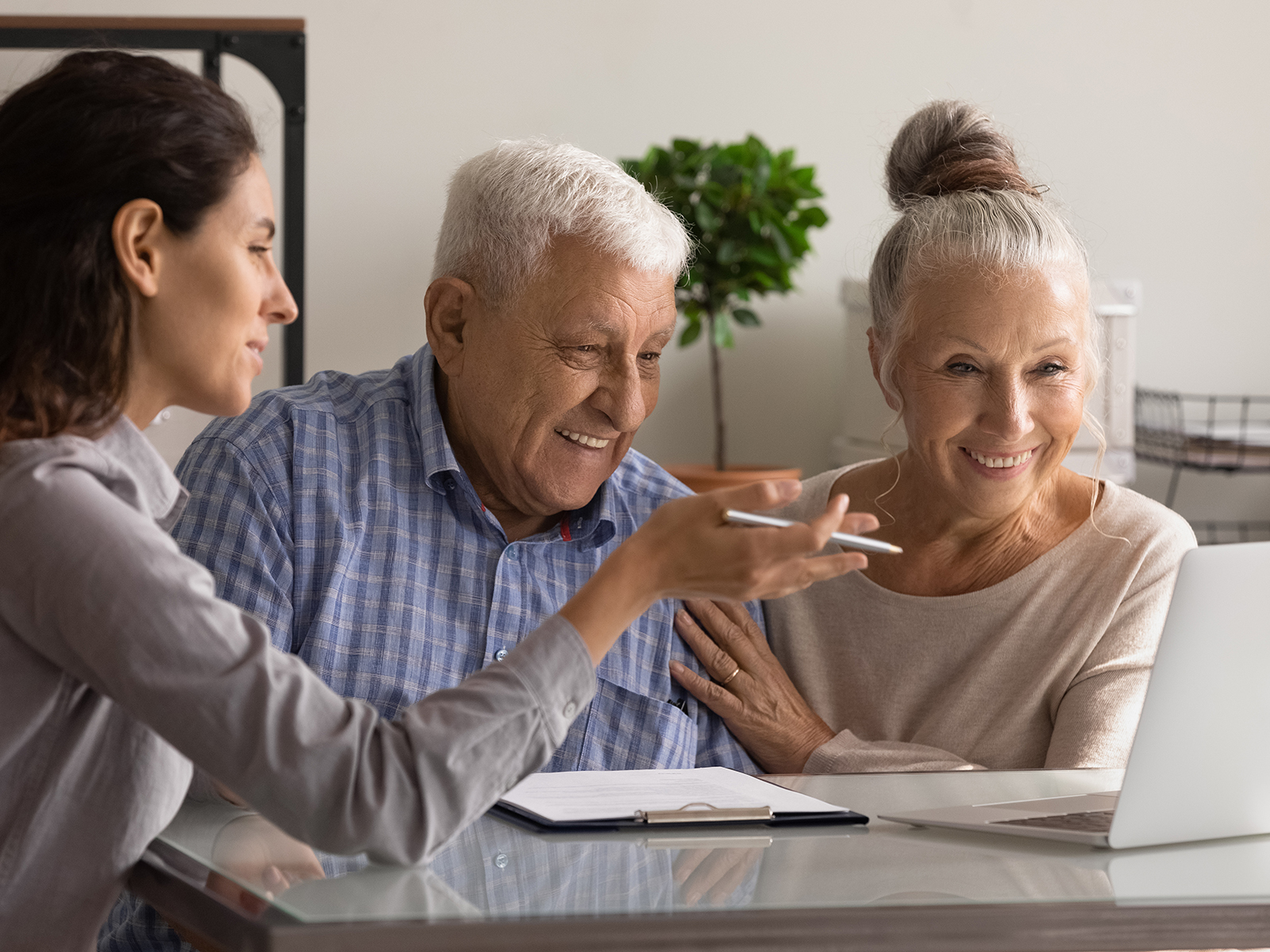 Woman helping senior couple on a laptop.