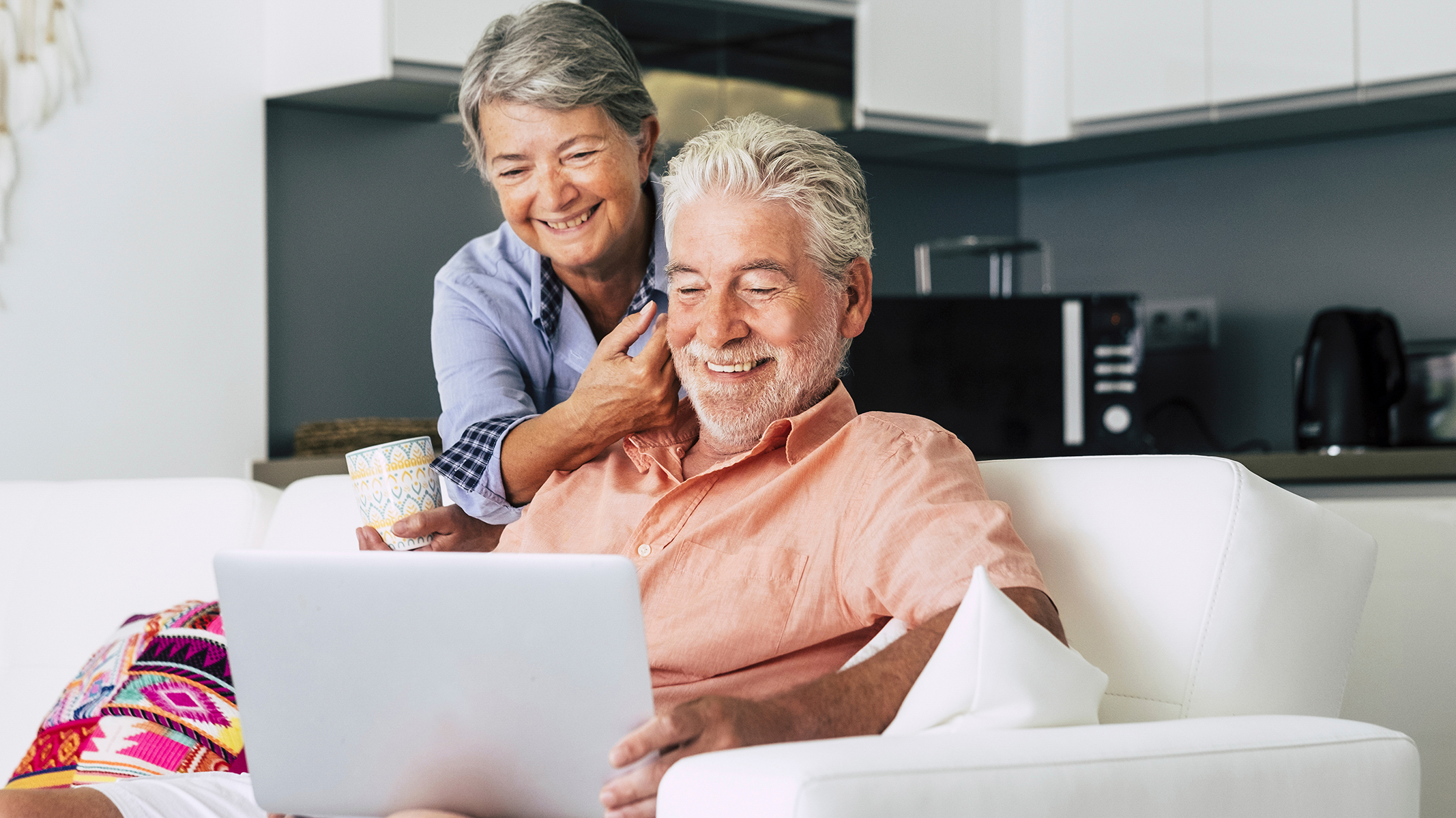 Senior couple smiling while looking at laptop