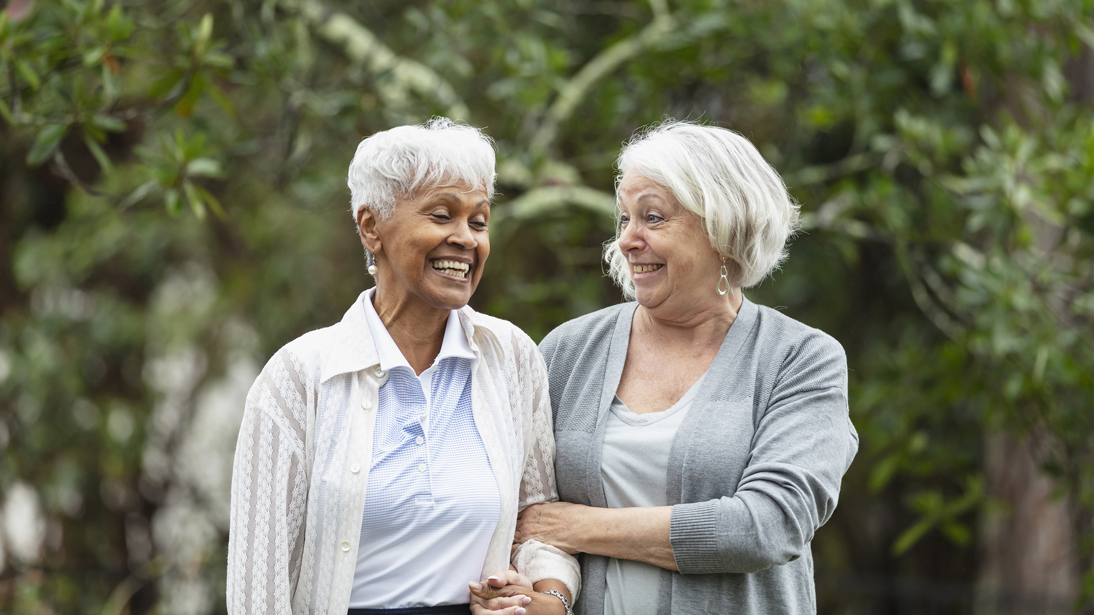 Two senior women walking and talking outside.