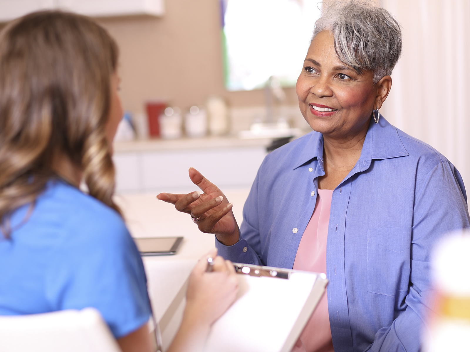 Senior woman and healthcare provider talking in doctor's office.