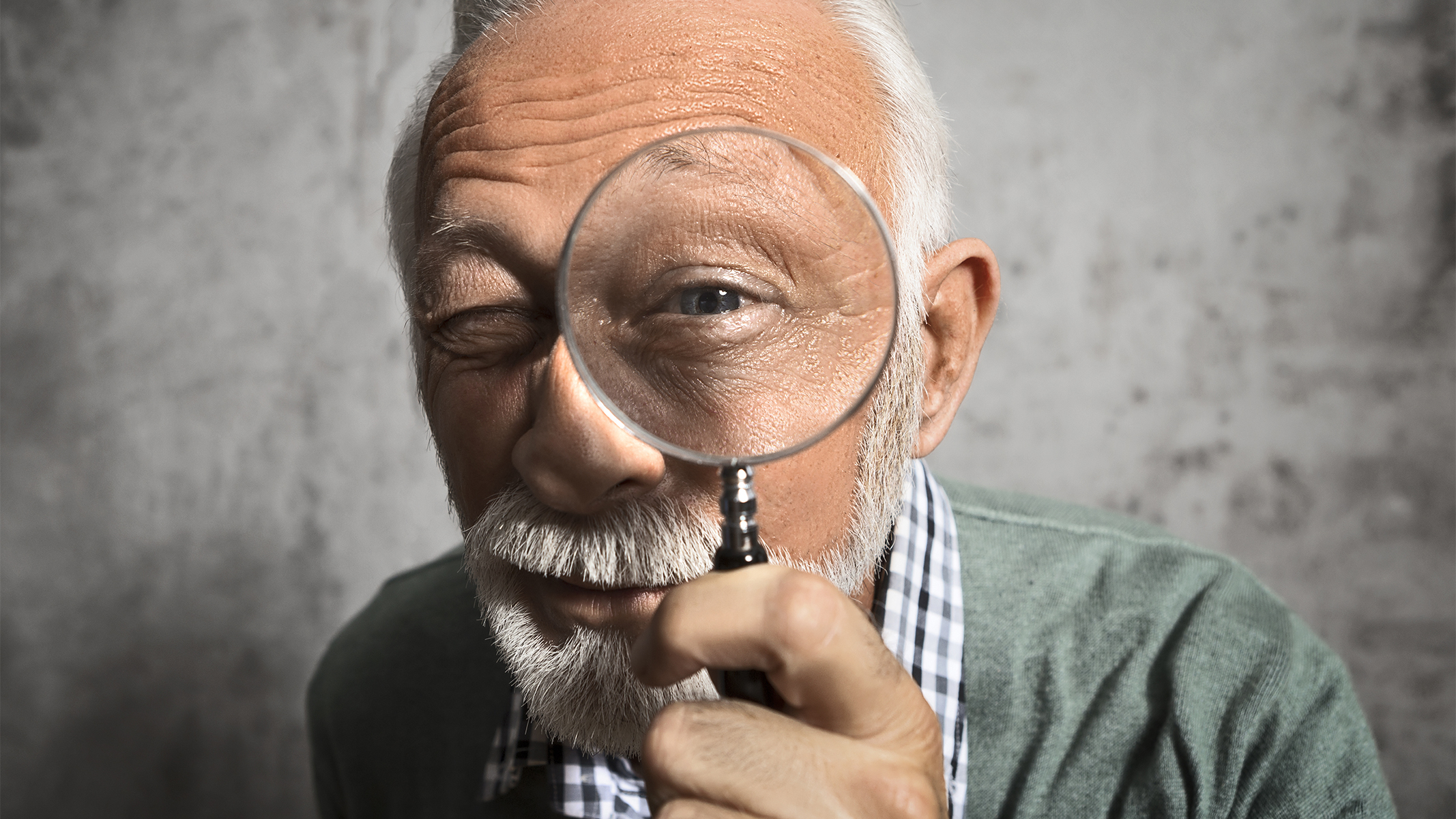 Close up of a senior looking through a magnifying glass.